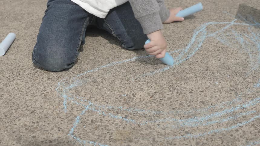 A person is drawing with chalk on the ground