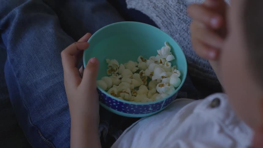 A child eats popcorn out of a bowl