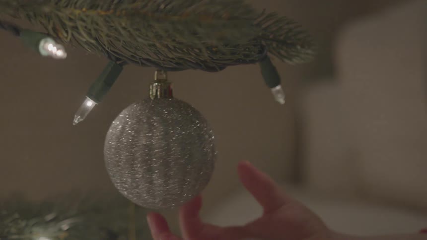 A child spins an ornament hanging from a christmas tree