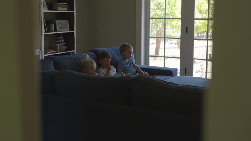 Three young boys sit on a couch together