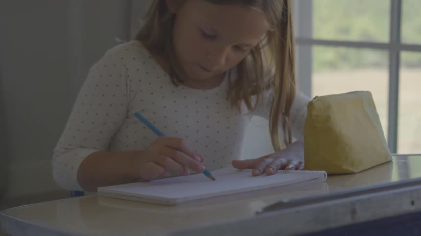 A child draws in a notebook at a desk