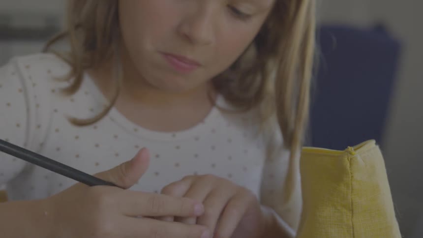 A white girl takes a pencil from a bag and starts writing