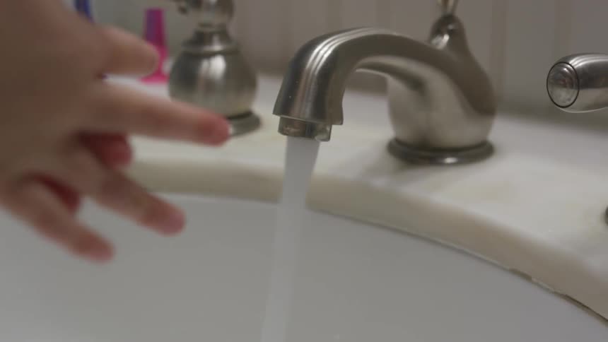 A young person washing their hands using soap and water in the bathroom