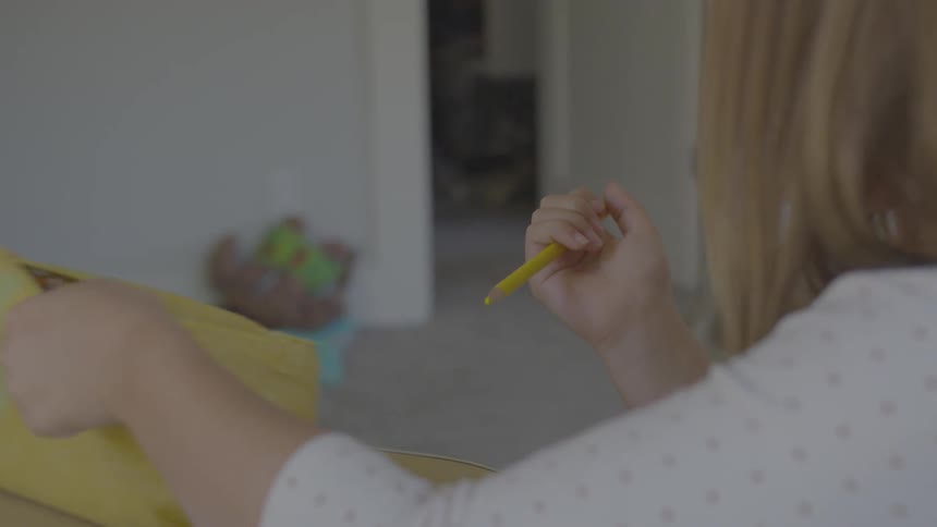 A girl removes a coloring pencil from a case