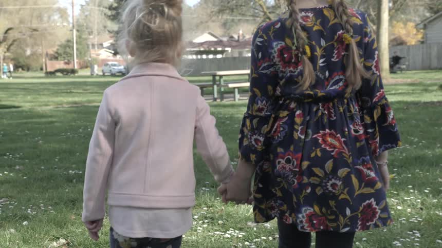 Two people walk hand in hand toward the picnic table