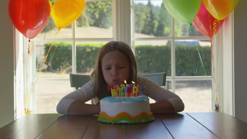 A young girl blows out candles on her birthday cake