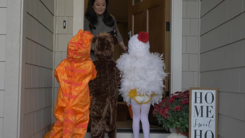 Children in costumes go up to a door on halloween