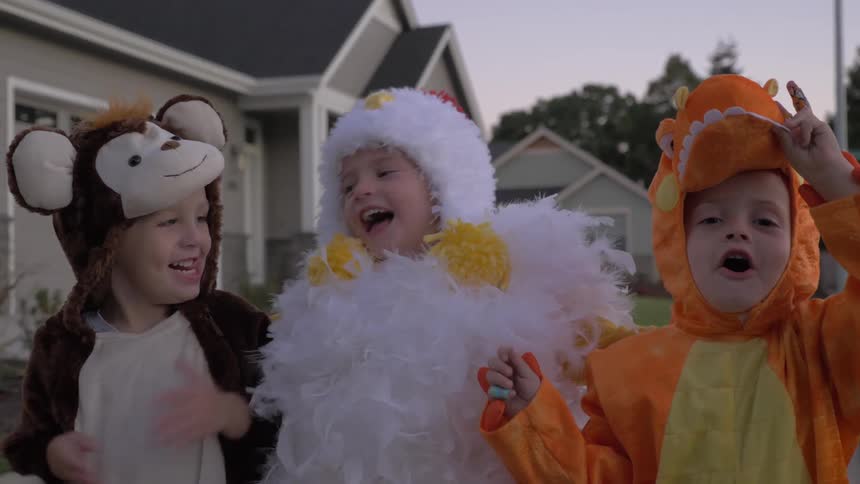 Three children standing around in costumes laughing