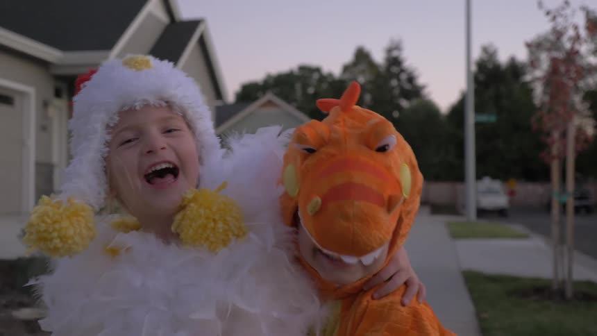 Two children laugh while wearing halloween costumes