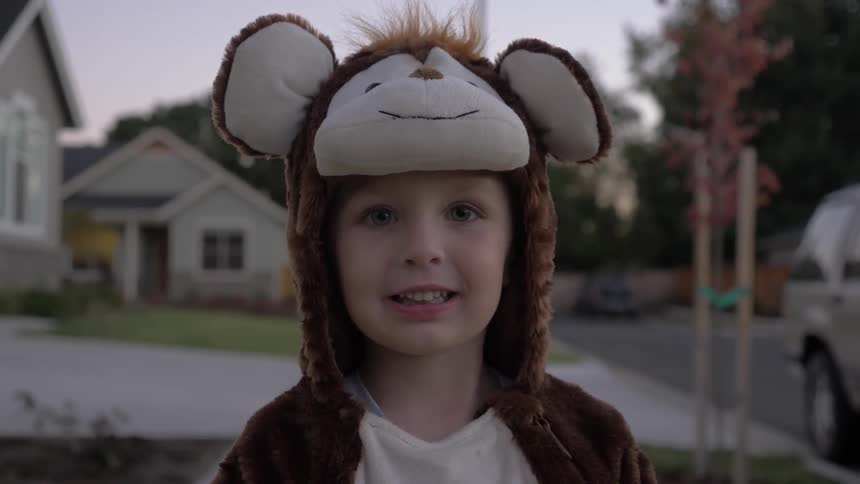 Child wearing halloween costume smiles in the neighborhood at dusk