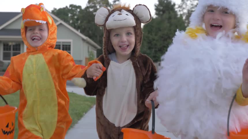 Children are running on the sidewalk going trick or treating