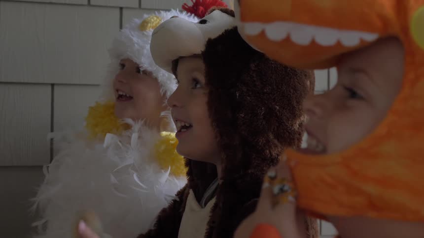 Children in costumes look at something out of frame smiling