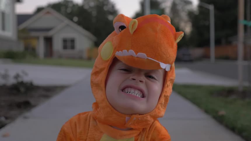 A boy in a dinosaur costume bares his teeth