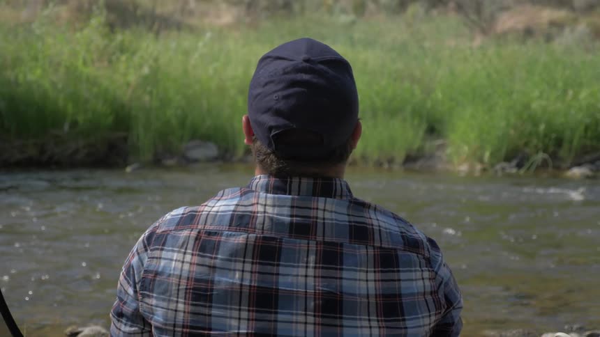 A man is standing by the stream