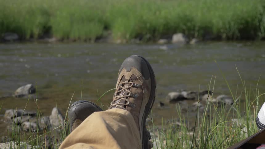 A person rests beside a river