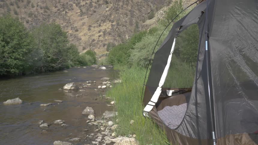 Tent borders river near low mountain