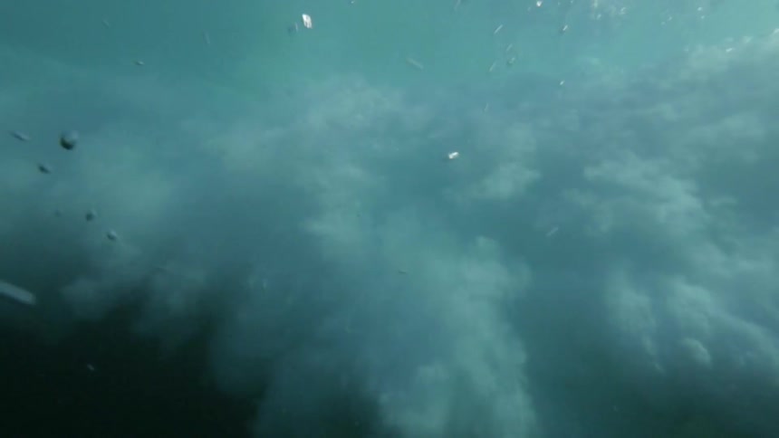 Epic underwater view of a wave passing overhead and crashing into a turbulent chaos