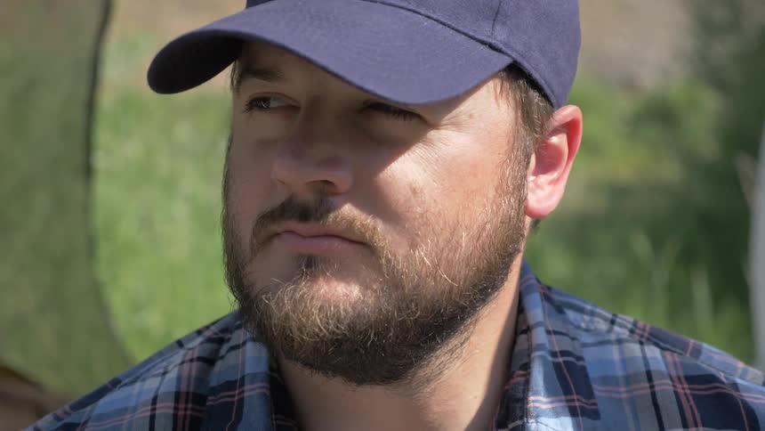 A man looks from side to side wearing a baseball cap