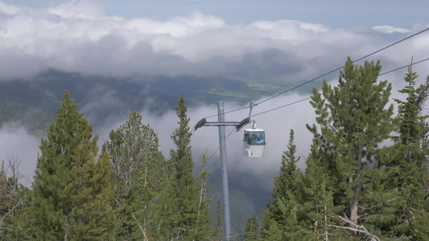 A gondola lift ascending a mountain during the day