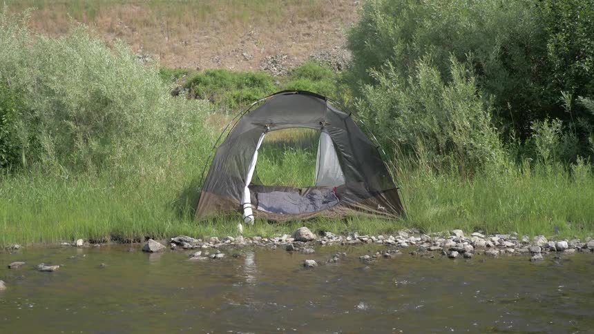 A tent is open near the water