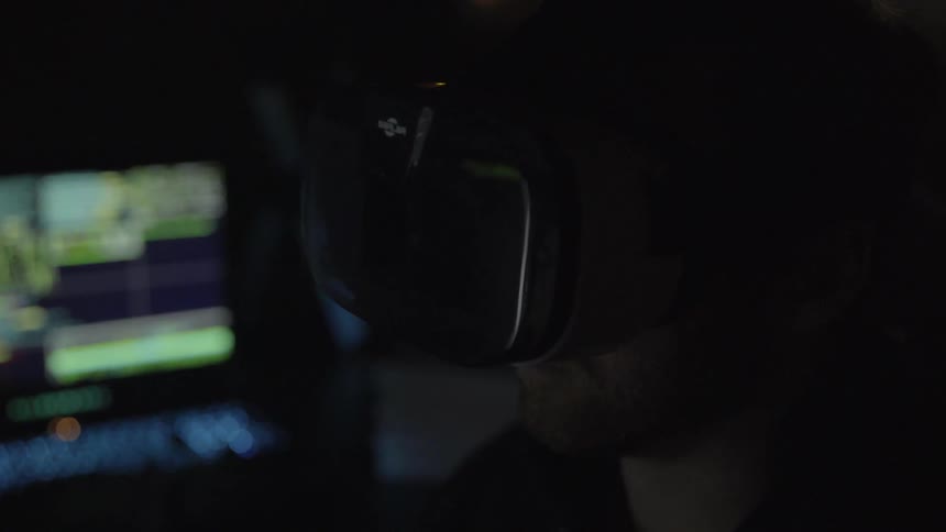 A man uses a virtual reality headset in a dark room
