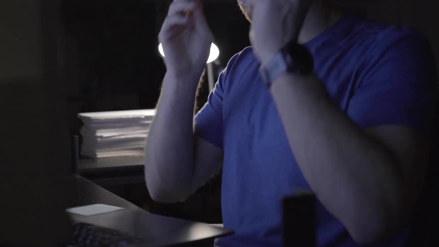 Man sitting in front of laptop puts on glasses