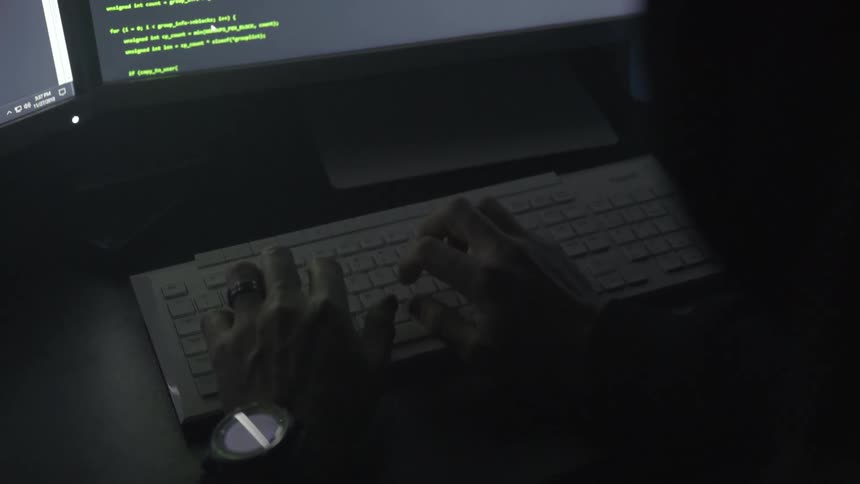 Man types on a keyboard as text appears on a monitor