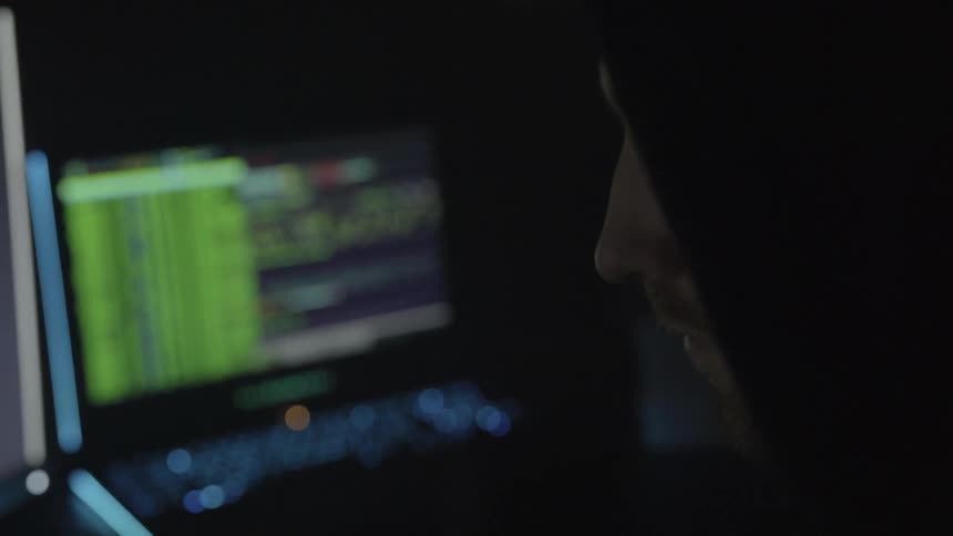 A man in a hoodie using computers