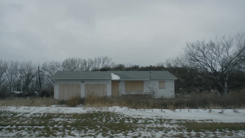 A small boarded up house in a rural area