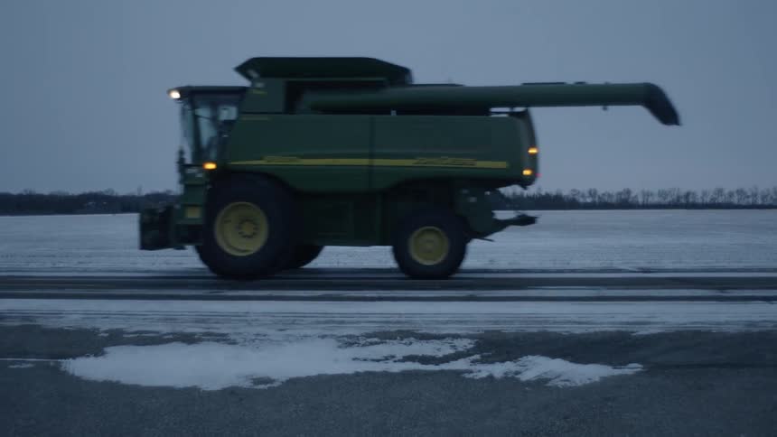 A work truck drives along a snowy road