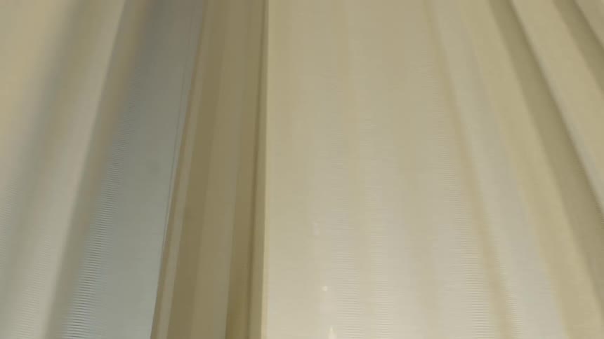 Curtains being pulled closed over a large window