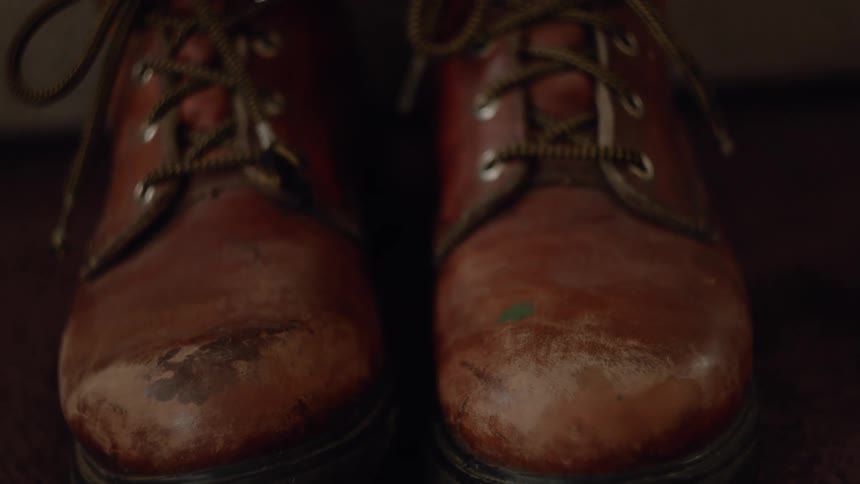 A person wearing leather boots tilts their right foot