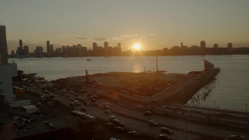 Cars drive on highway near water at dusk