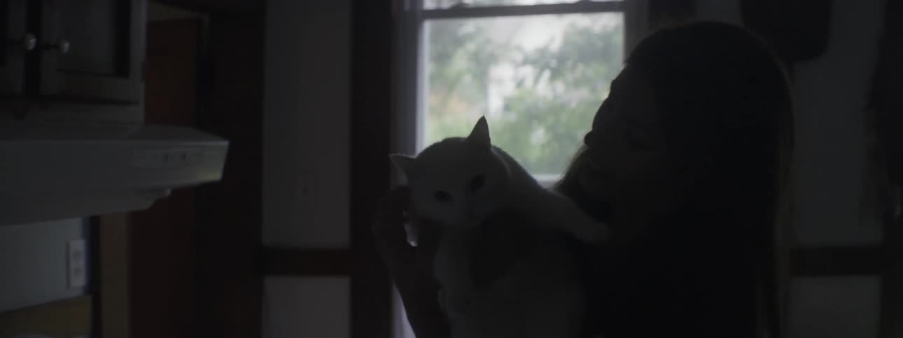 Woman lifts her cat from the kitchen floor