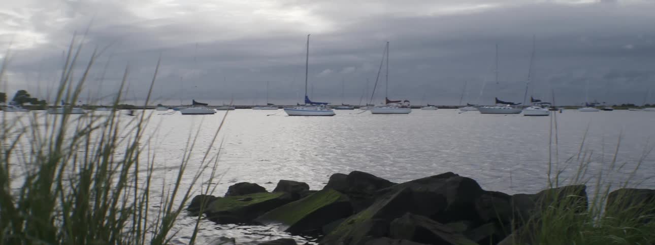 Boats float on the ocean on an overcast day