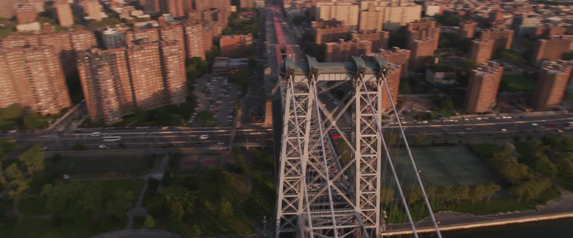 The camera flies over a river and bridge near a large city