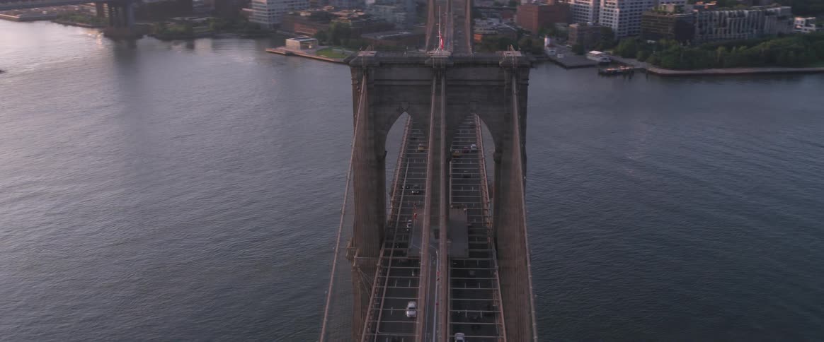 The camera flies over a bridge next to a large city