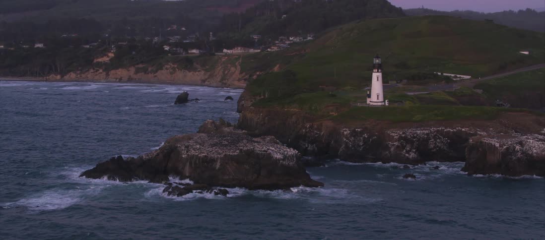 Aerial view of a lighthouse on a cliff at sunset