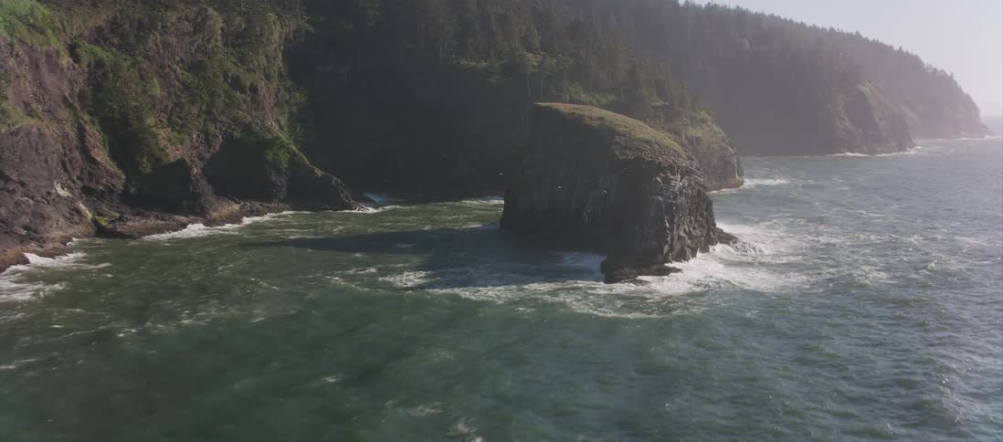 The camera flies by a rugged ocean coastline