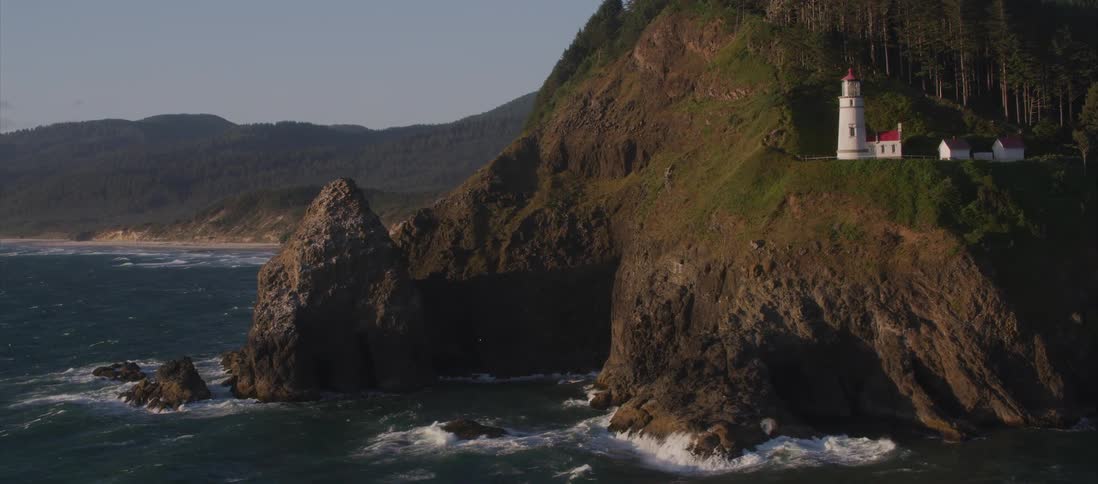An aerial shot of a lighthouse on a cliff