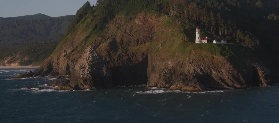 An aerial shot of a coastline with a lighthouse