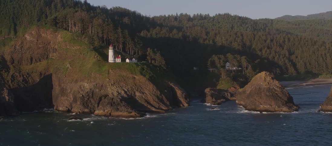 An aerial shot of a lighthouse on a cliff