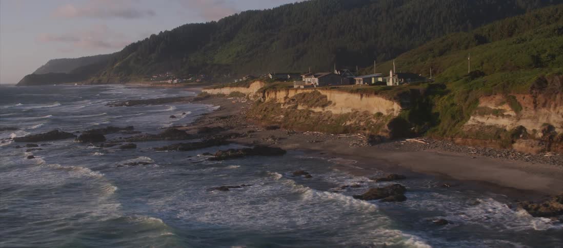 Homes overlook the ocean as waves crash into the shoreline