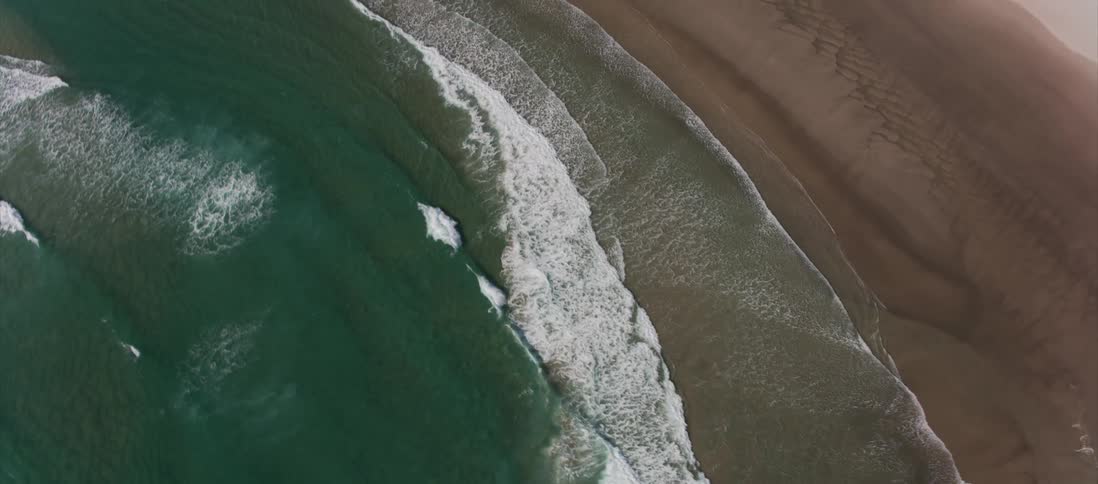 Waves crash in the turquoise ocean next to the beach