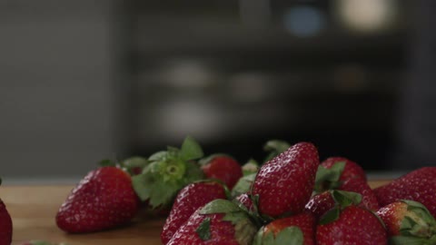 Strawberries are poured from a bowl onto a table