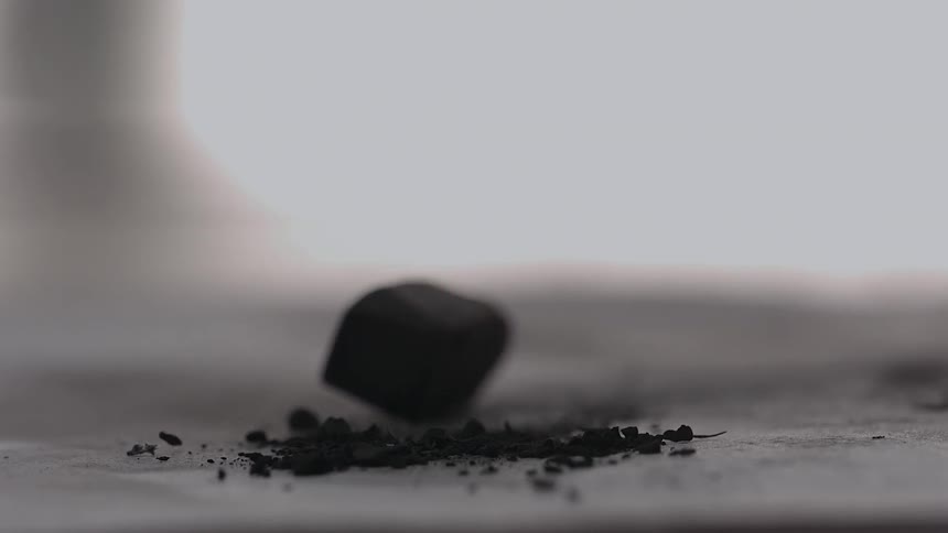 A piece of charcoal drops onto a surface