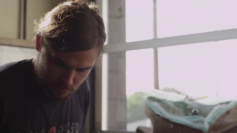 A man scoops coffee beans from a bin