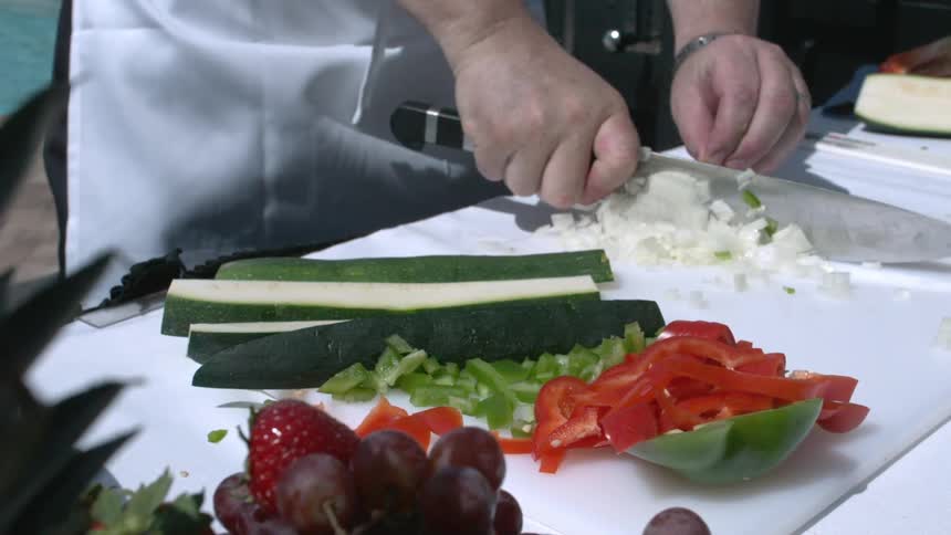 A knife chops vegetables on a cutting board