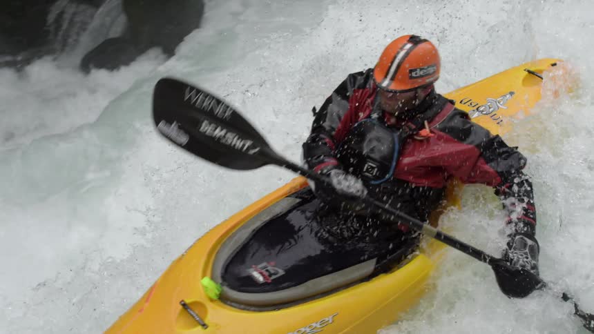 A man in a yellow kayak paddles down a large drop deep in the whitewater wilderness of the Pacific Northwest