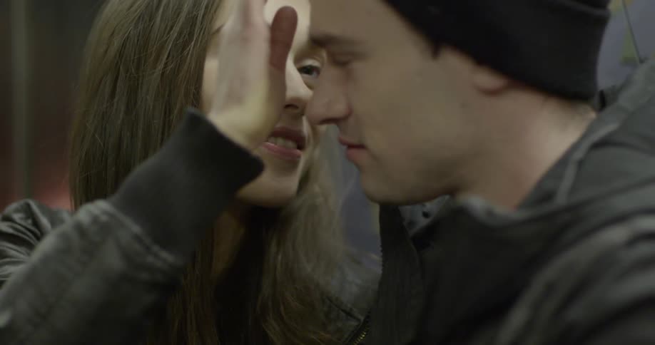 A man and woman look lovingly at each other while talking, and then she fixes his hair under his cap